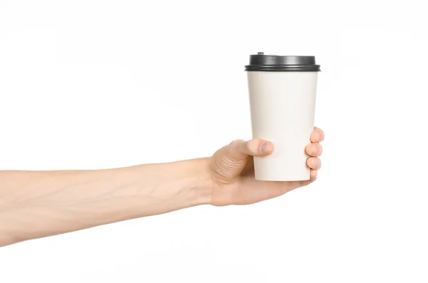 Breakfast and coffee theme: man's hand holding white empty paper coffee cup with a brown plastic cap isolated on a white background in the studio, advertising coffee — Stock Photo, Image