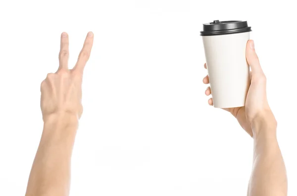 Breakfast and coffee theme: man's hand holding white empty paper coffee cup with a brown plastic cap isolated on a white background in the studio, advertising of coffee first-person view — Stock Photo, Image