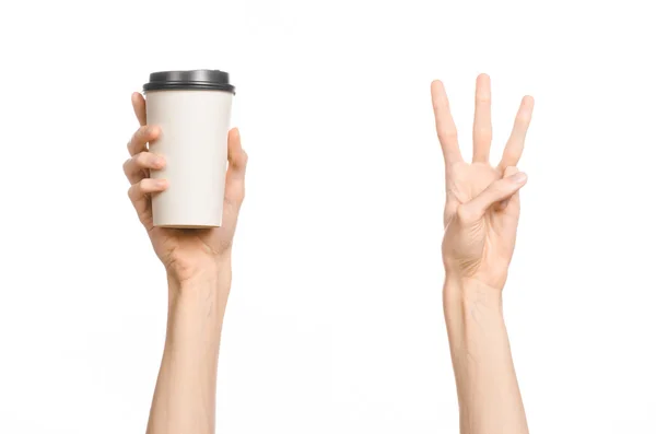 Frukost och kaffe tema: mannens hand håller vitt tomt papper kaffekopp med en brun plast mössa isolerad på en vit bakgrund i studion, reklam kaffe — Stockfoto