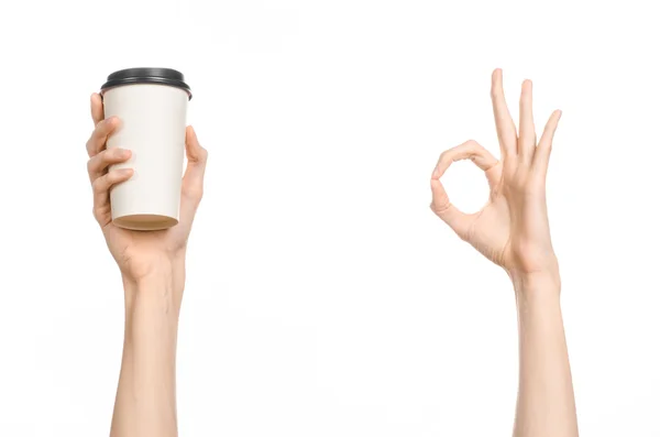 Tema colazione e caffè: mano dell'uomo che tiene la tazza di caffè di carta bianca vuota con un tappo di plastica marrone isolato su uno sfondo bianco in studio, caffè pubblicitario — Foto Stock