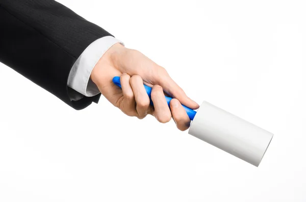 Dry cleaning and business theme: a man in a black suit holding a blue sticky brush for cleaning clothes and furniture from dust isolated on white background in studio. — ストック写真