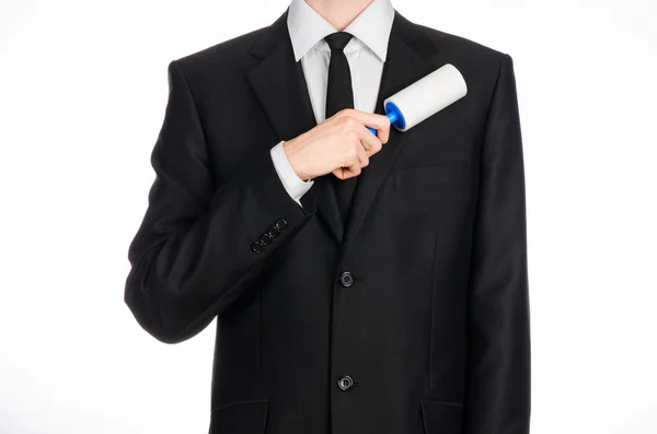 Dry cleaning and business theme: a man in a black suit holding a blue sticky brush for cleaning clothes and furniture from dust isolated on white background in studio. — Φωτογραφία Αρχείου