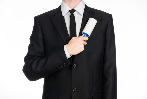 Dry cleaning and business theme: a man in a black suit holding a blue sticky brush for cleaning clothes and furniture from dust isolated on white background in studio. — Φωτογραφία Αρχείου