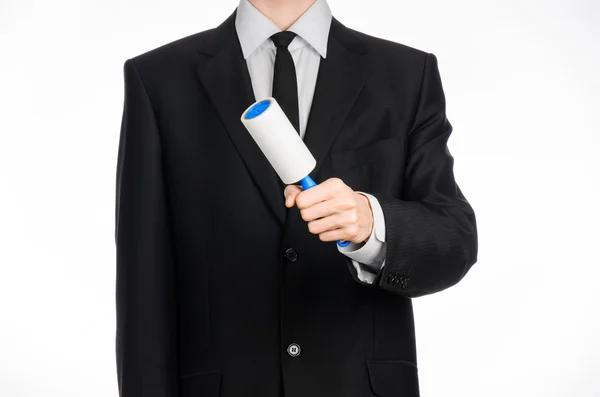 Limpeza a seco e tema de negócios: um homem de terno preto segurando uma escova pegajosa azul para limpar roupas e móveis de poeira isolada em fundo branco no estúdio . — Fotografia de Stock