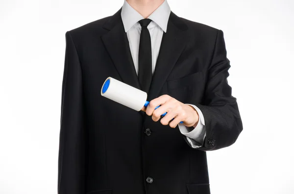 Limpeza a seco e tema de negócios: um homem de terno preto segurando uma escova pegajosa azul para limpar roupas e móveis de poeira isolada em fundo branco no estúdio . — Fotografia de Stock