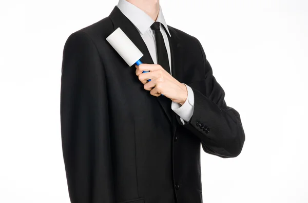 Dry cleaning and business theme: a man in a black suit holding a blue sticky brush for cleaning clothes and furniture from dust isolated on white background in studio. — 스톡 사진