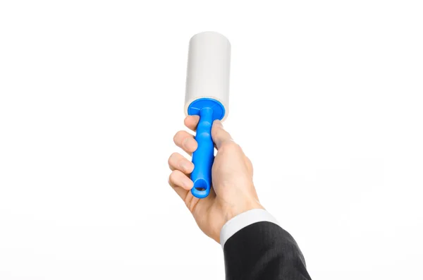 Dry cleaning and business theme: a man in a black suit holding a blue sticky brush for cleaning clothes and furniture from dust isolated on white background in studio. — Stockfoto