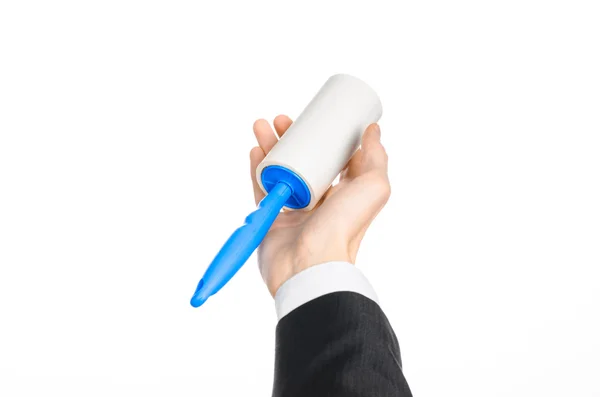 Dry cleaning and business theme: a man in a black suit holding a blue sticky brush for cleaning clothes and furniture from dust isolated on white background in studio. — Stock Photo, Image