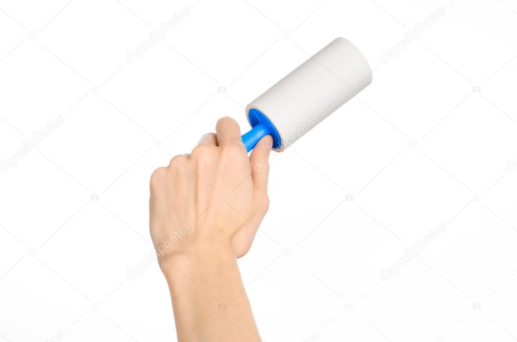 Clean clothes and cleaning the house topic: human hand holding a blue sticky brush for cleaning clothes and furniture from dust isolated on white background in studio.