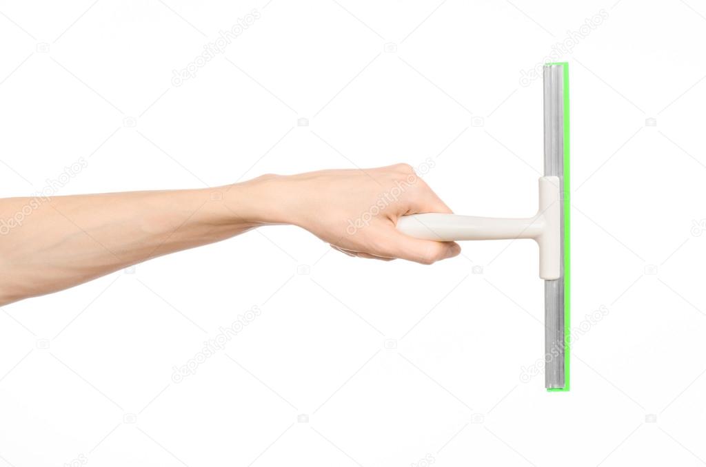 Household cleaning and washing windows theme: man's hand holding a green scraper windows isolated on a white background in the studio.