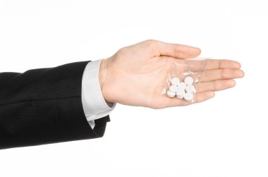 Addiction and business topic: hand in a black suit holds bag with white pills a drug on a white isolated background in studio