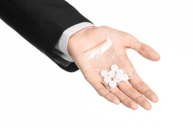 Addiction and business topic: hand in a black suit holds bag with white pills a drug on a white isolated background in studio