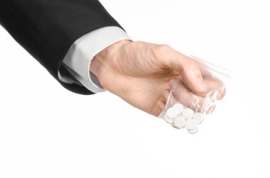 Addiction and business topic: hand in a black suit holds bag with white pills a drug on a white isolated background in studio