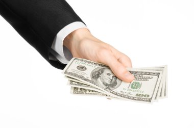 Money and business topic: hand in a black suit holding a banknote of 100 dollars on white isolated background in studio