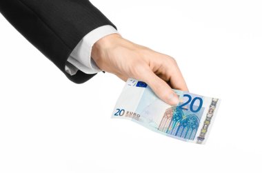 Money and business topic: hand in a black suit holding a banknote 20 euro isolated on a white background in studio