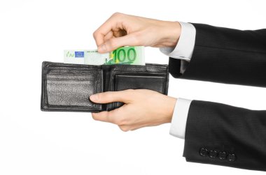 Money and business topic: hand in a black suit holding a wallet with 100 euro banknotes isolated on white background in studio