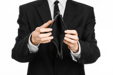 Poverty and money theme: a man in a black suit holding a empty purse isolated on white background in studio