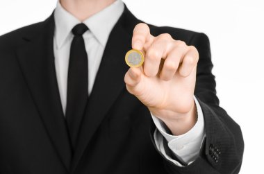Money and business theme: a man in a black suit holding a coin 1 Euro in the studio on a white background isolated