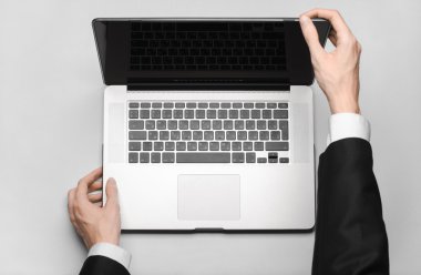 Business and technology topic: the hand of man in a black suit showing gesture against a gray and white background laptop in the studio isolated top view