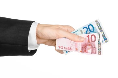 Money and business topic: hand in a black suit holding banknotes 10 and 20 euro on white isolated background in studio