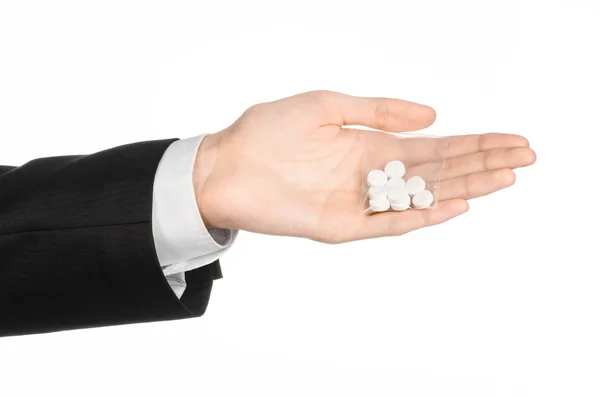 Vício e tópico de negócios: mão em um terno preto mantém saco com pílulas brancas uma droga em um fundo isolado branco no estúdio — Fotografia de Stock