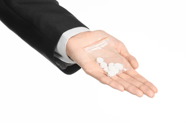 Adicción y tema de negocios: mano en un traje negro sostiene bolsa con píldoras blancas una droga sobre un fondo blanco aislado en el estudio — Foto de Stock