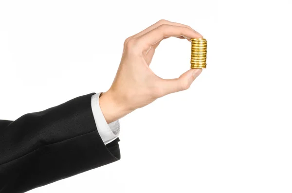 Dinheiro e tópico de negócios: mão em um terno preto segurando uma pilha de moedas de ouro no estúdio em um fundo branco isolado — Fotografia de Stock