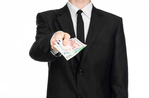 Money and business theme: a man in a black suit is holding euro money isolated on white background in studio — Stockfoto