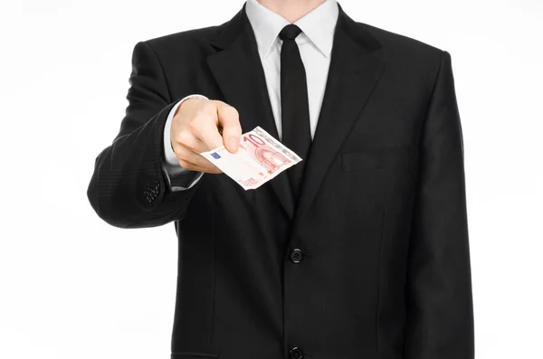 Money and business theme: a man in a black suit holding a bill of 10 euros and shows a hand gesture on an isolated white background in studio — 스톡 사진