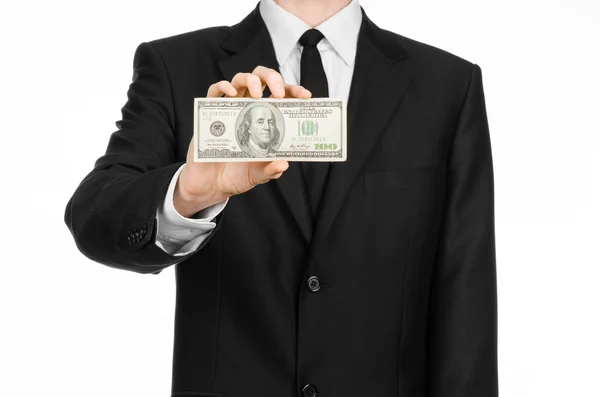 Geld und Geschäftsthema: Ein Mann im schwarzen Anzug hält einen Schein über 100 Dollar in der Hand und zeigt eine Handgeste auf einem isolierten weißen Hintergrund im Studio — Stockfoto