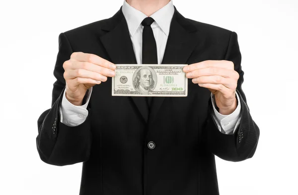 Geld und Geschäftsthema: Ein Mann im schwarzen Anzug hält einen Schein über 100 Dollar in der Hand und zeigt eine Handgeste auf einem isolierten weißen Hintergrund im Studio — Stockfoto