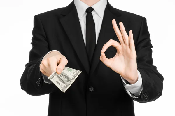 Dinheiro e tema de negócios: um homem de terno preto segurando uma nota de 100 dólares e apresenta um gesto de mão em um fundo branco isolado em estúdio — Fotografia de Stock