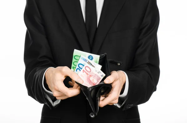 Money and business theme: a man in a black suit holding a purse with paper money Euro isolated on white background in studio — 图库照片