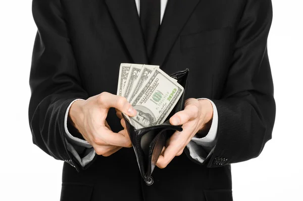 Money and business theme: a man in a black suit holding a purse with paper money dollars isolated on white background in studio — Stock Fotó