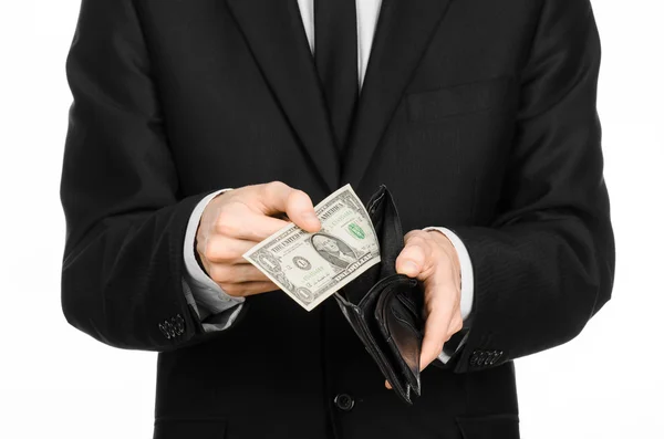 Pobreza e dinheiro tema: um homem de fato preto segurando uma carteira vazia e nota 1 dólar sobre fundo branco isolado em estúdio — Fotografia de Stock