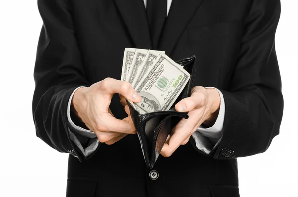 Dinero y tema de negocios: un hombre con un traje negro sosteniendo un bolso con dólares de papel moneda aislado sobre fondo blanco en el estudio — Foto de Stock