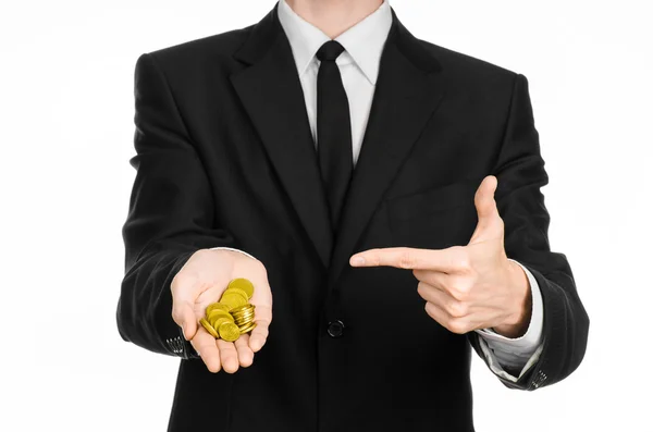 Money and business theme: a man in a black suit holding a pile of gold coins in the studio on a white background isolated — 图库照片