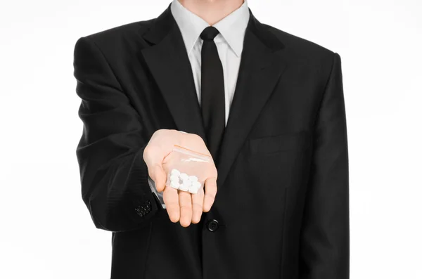 Addiction and business topic: hand in a black suit holds bag with white pills a drug on a white isolated background in studio — 스톡 사진