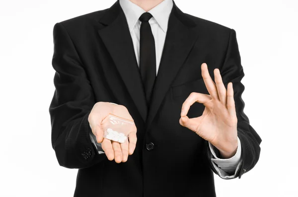 Dipendenza e business topic: mano in un abito nero tiene borsa con pillole bianche una droga su uno sfondo bianco isolato in studio — Foto Stock