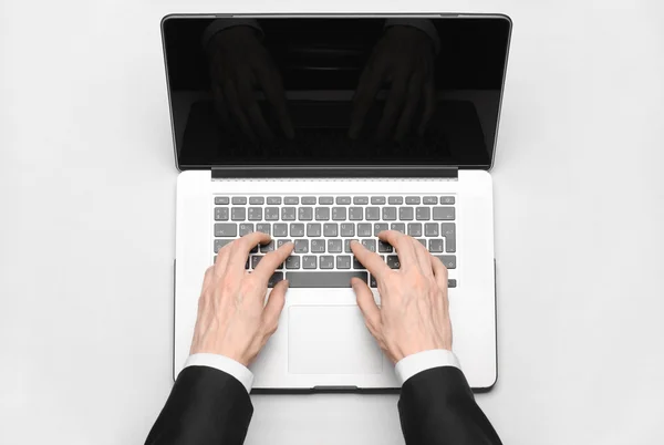Tema de negocios y tecnología: la mano del hombre en un traje negro mostrando gesto contra un portátil de fondo gris y blanco en el estudio vista superior aislada — Foto de Stock