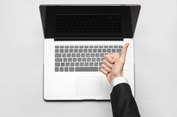 Business and technology topic: the hand of man in a black suit showing gesture against a gray and white background laptop in the studio isolated top view