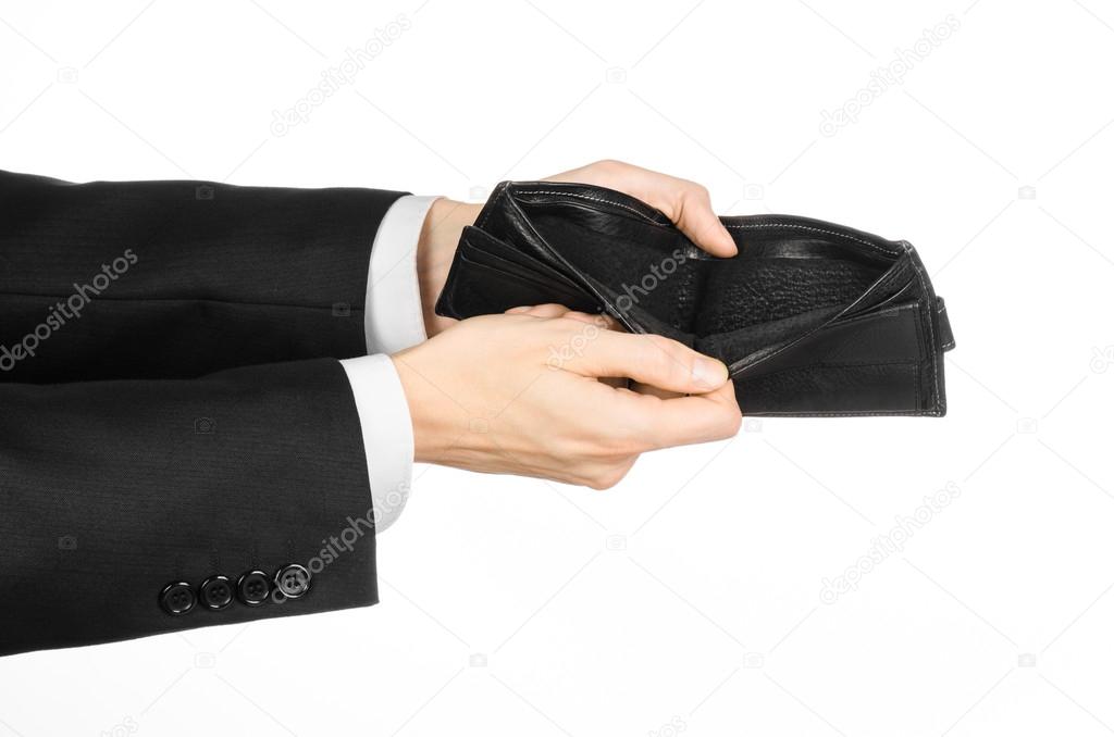 Poverty and money theme: a man in a black suit holding a empty purse isolated on white background in studio