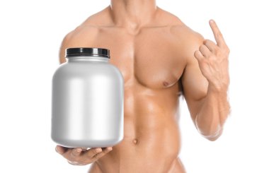Bodybuilding and Sports theme: handsome strong bodybuilder holding a plastic jar with a dry protein and showing gesture isolated on white background in studio