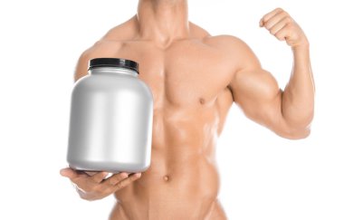 Bodybuilding and Sports theme: handsome strong bodybuilder holding a plastic jar with a dry protein and showing gesture isolated on white background in studio