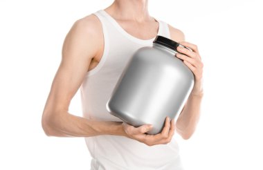 Bodybuilding and Sports theme: a thin man in a white T-shirt and jeans holding a plastic jar with a protein isolated on a white background in studio