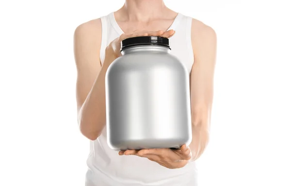 Bodybuilding and Sports theme: a thin man in a white T-shirt and jeans holding a plastic jar with a protein isolated on a white background in studio — Zdjęcie stockowe