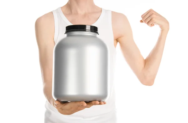 Bodybuilding and Sports theme: a thin man in a white T-shirt and jeans holding a plastic jar with a protein isolated on a white background in studio — Stock Fotó