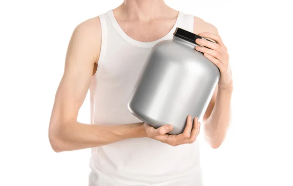 Bodybuilding and Sports theme: a thin man in a white T-shirt and jeans holding a plastic jar with a protein isolated on a white background in studio — ストック写真