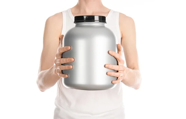 Bodybuilding and Sports theme: a thin man in a white T-shirt and jeans holding a plastic jar with a protein isolated on a white background in studio — Stock Photo, Image