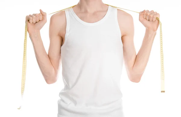Musculação e Esportes tema: um homem magro em uma camiseta branca e jeans com fita métrica isolada em um fundo branco em estúdio — Fotografia de Stock